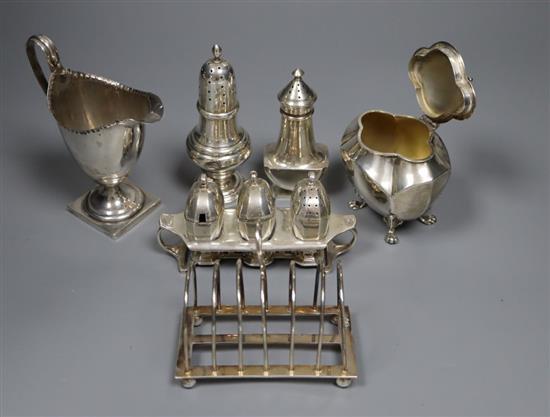 Small silver including a George V tea caddy, toastrack, cream jug, two pepperettes and a condiment set with stand, gross 20 oz.